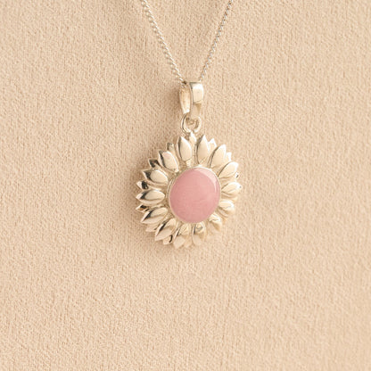 Sterling Silver Sunflower Ashes Necklace with a pink resin infill containing ashes or fur set on a beige textured background