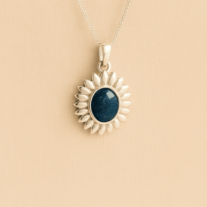 Silver Sunflower Memorial Necklace with a navy resin infill containing ashes or fur set on a beige textured background