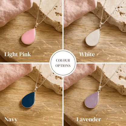 Teardrop ashes necklaces in light pink, white, navy, and lavender on a wooden surface.
