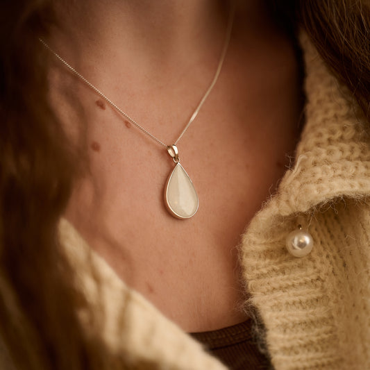 Sterling silver cremation necklace worn by woman – teardrop shape with white resin