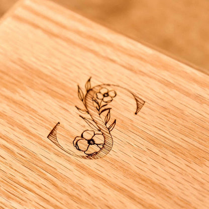 A close up of an engraving on a personalised cremation urn. The letter S is shown with a floral design. Personalised urn.