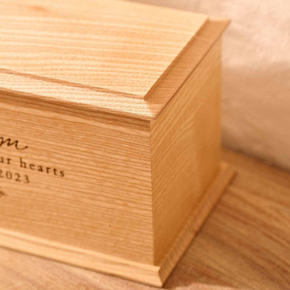 Close-up of engraved ash wood cremation urn with floral design for women – detailed view of custom memorial