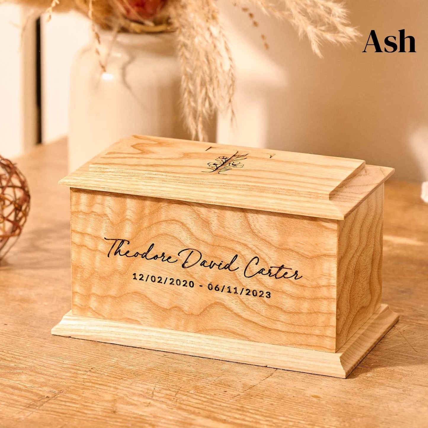 A wooden cremation urn for ashes. The cremation urn is rectangular and is made of ash. It is a personalised urn for a child.