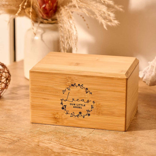 Personalised infant cremation urn with floral wreath engraving – baby urn for stillborn, child, or miscarriage ashes, engraved with “Lucas – Our Little Angel”.