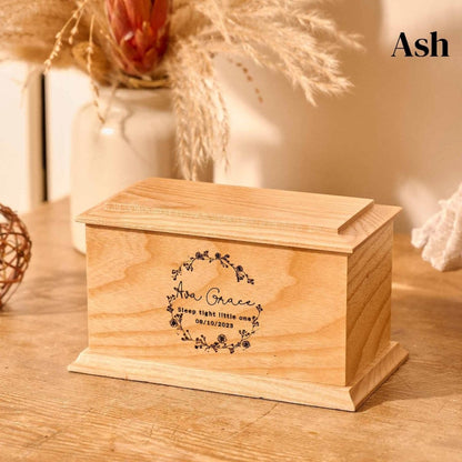 Wooden cremation urn for stillborn baby – ash wood urn engraved with wreath design, name, and memorial message.