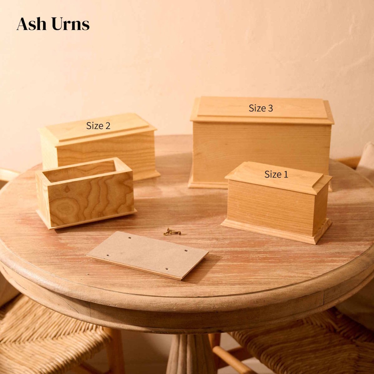 Ash wood cremation urns in Sizes 1–3 on round table – rectangular urns with bevelled edges, one small urn shown open with lid and screws.