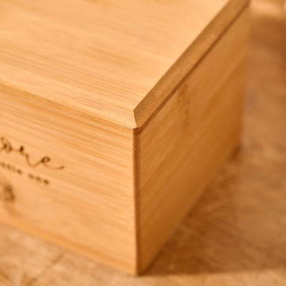 A small cremation urn for a stillborn baby or a miscarriage sits on a table. It is engraved with a cloud and rainbow motif and the name "theodore". A message reads "sleep tight little one". It is a personalised cremation urn.